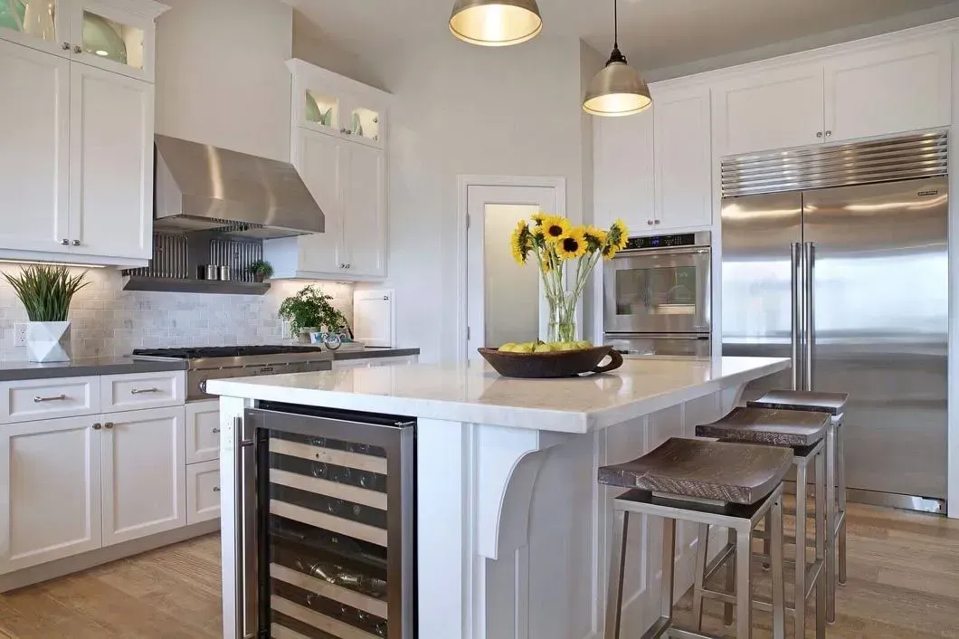 White kitchen with island, stainless steel appliances, and sunflowers in vase.