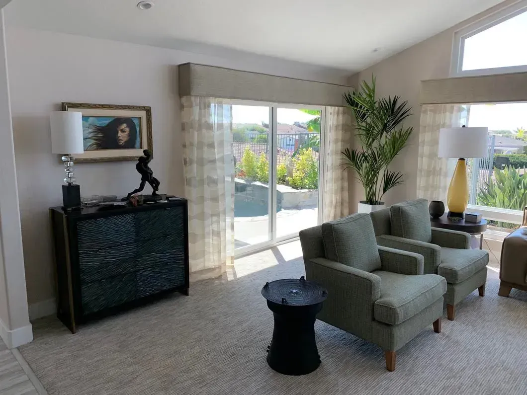 Living room with green armchairs, large sliding glass doors, and decorative furniture.