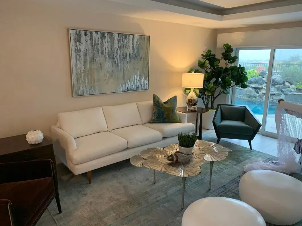 Living room with a white sofa, abstract art, and a view of a pool.