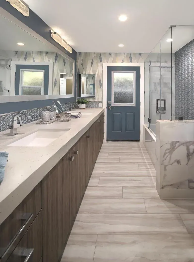 Long bathroom with wood cabinets, light tile floor, blue door, and marble accents.