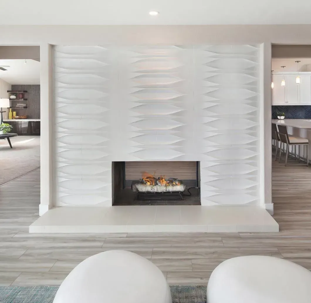 Modern white fireplace with textured wall, flames, and light gray stone hearth.