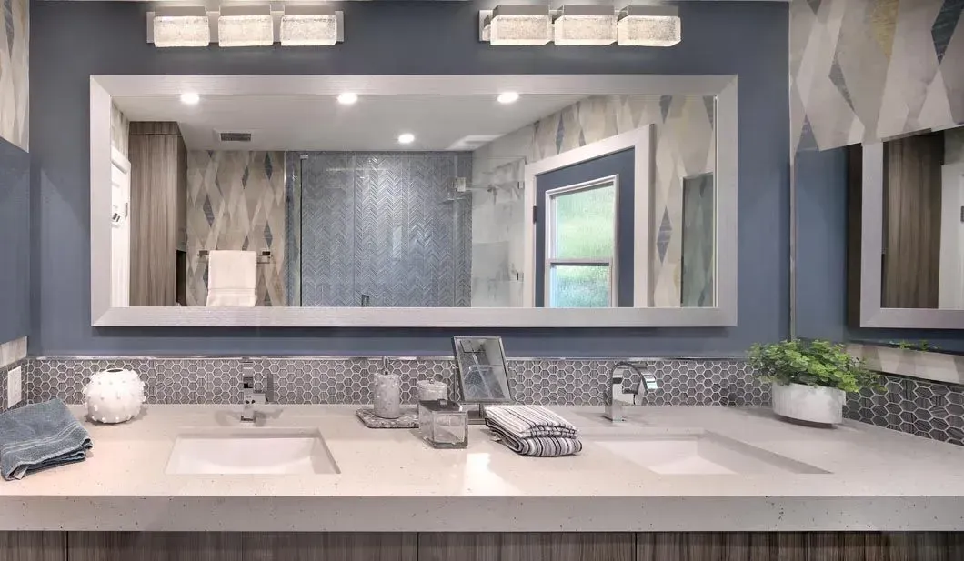 Bathroom with a large mirror, dual sinks, blue walls, and mosaic tile backsplash.