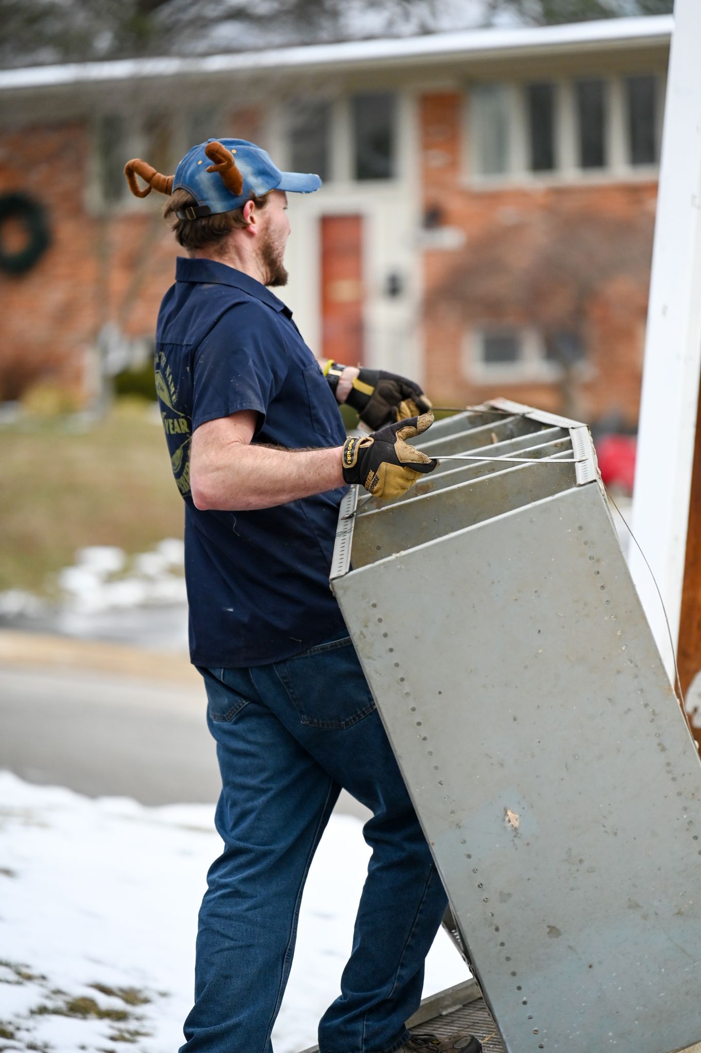 A man is carrying a piece of metal in front of a house.