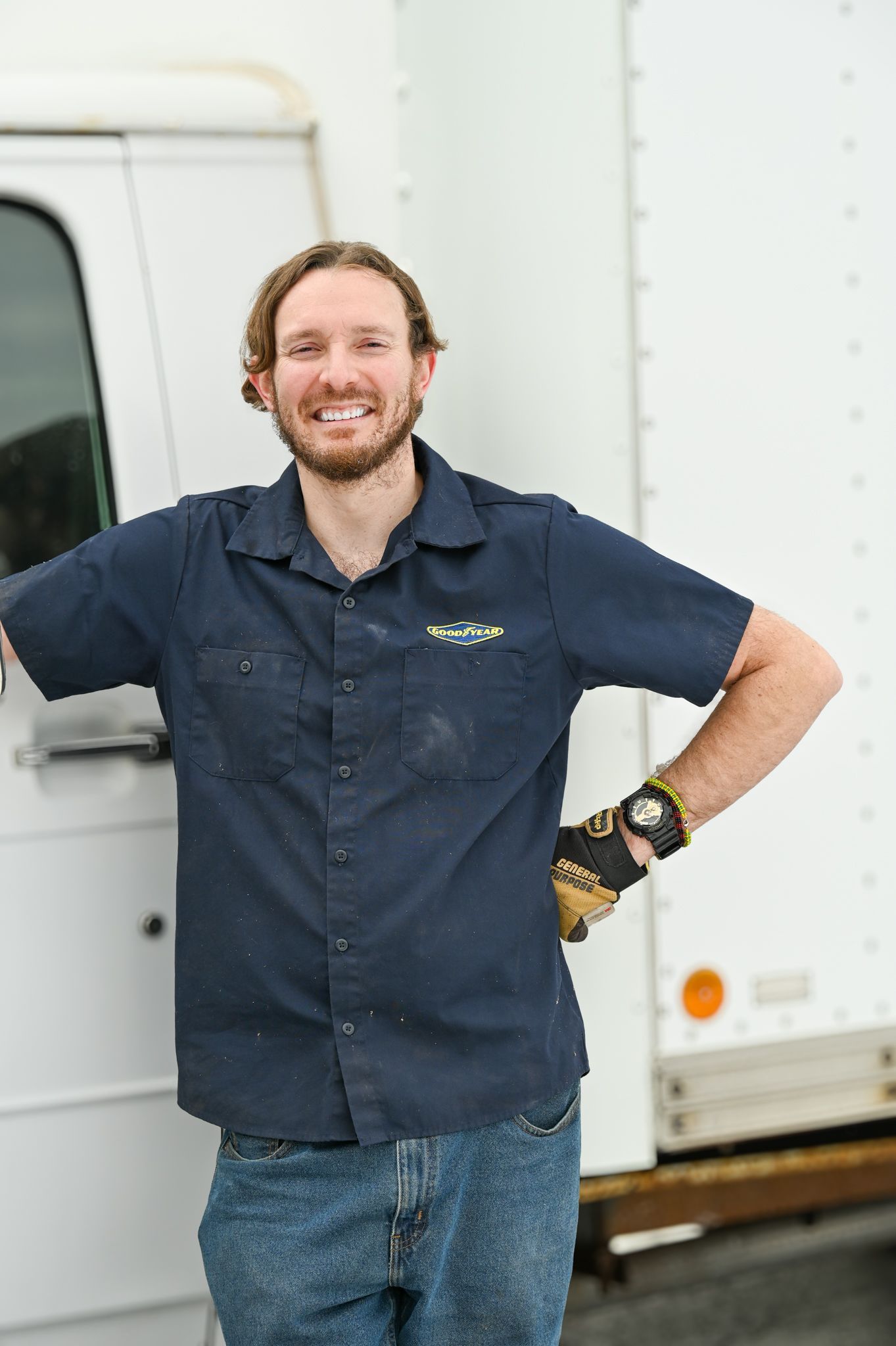 A man in a blue shirt is standing in front of a white truck.