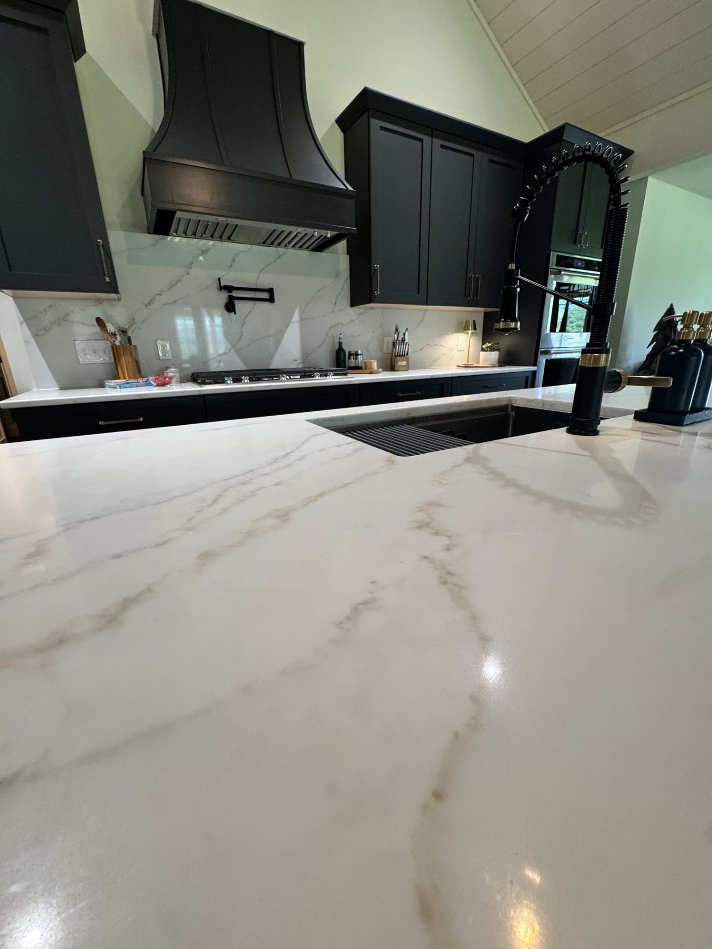 Built-in wooden kitchen cabinet with glass doors, dark countertop, and flowers on the left side.