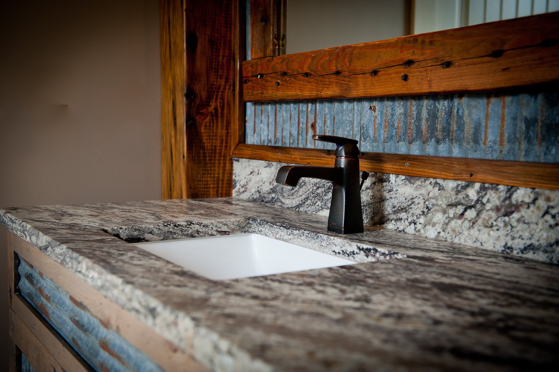 Modern bathroom vanity with white sink, black faucet, and granite countertop