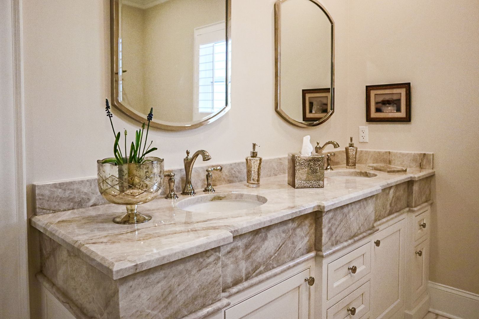 Elegant bathroom vanity with double sinks, marble countertop, mirrors, and gold fixtures