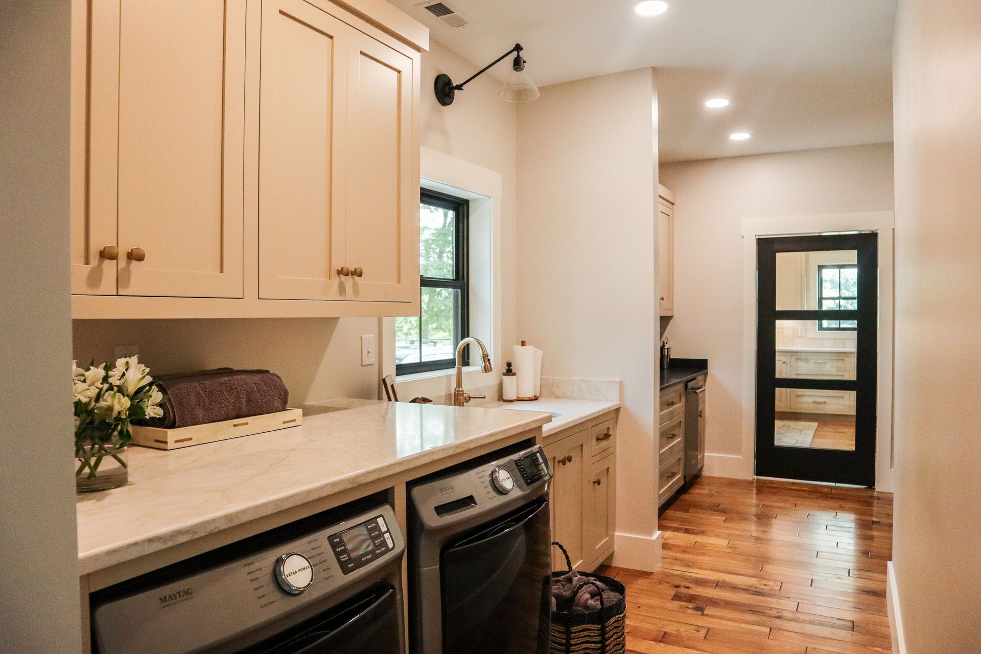 Bright kitchen with beige cabinets, white countertops, stainless appliances, and a black-framed glass door.