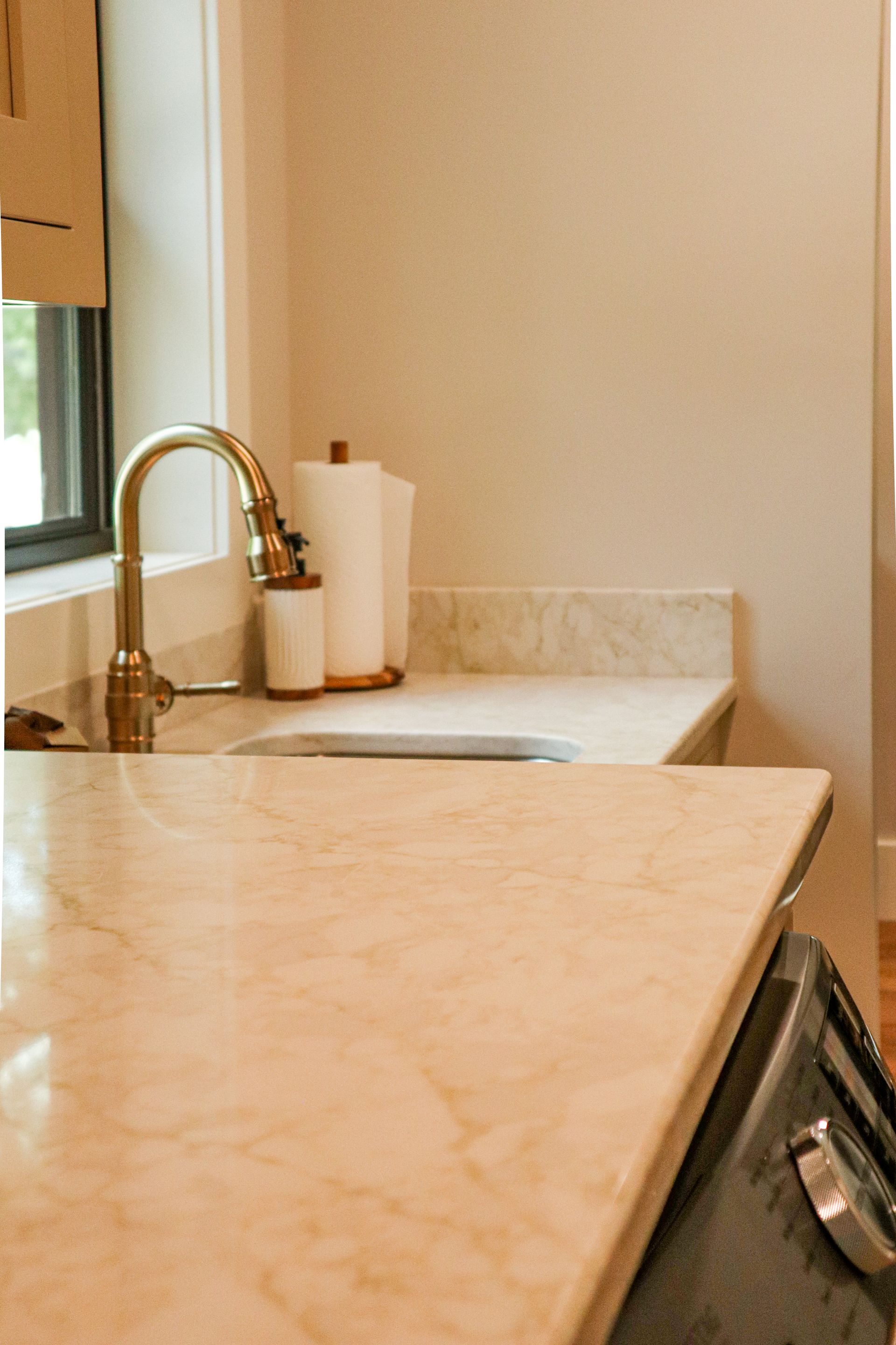 Kitchen counter with sink, chrome faucet, paper towel roll, and stainless steel appliance at right.