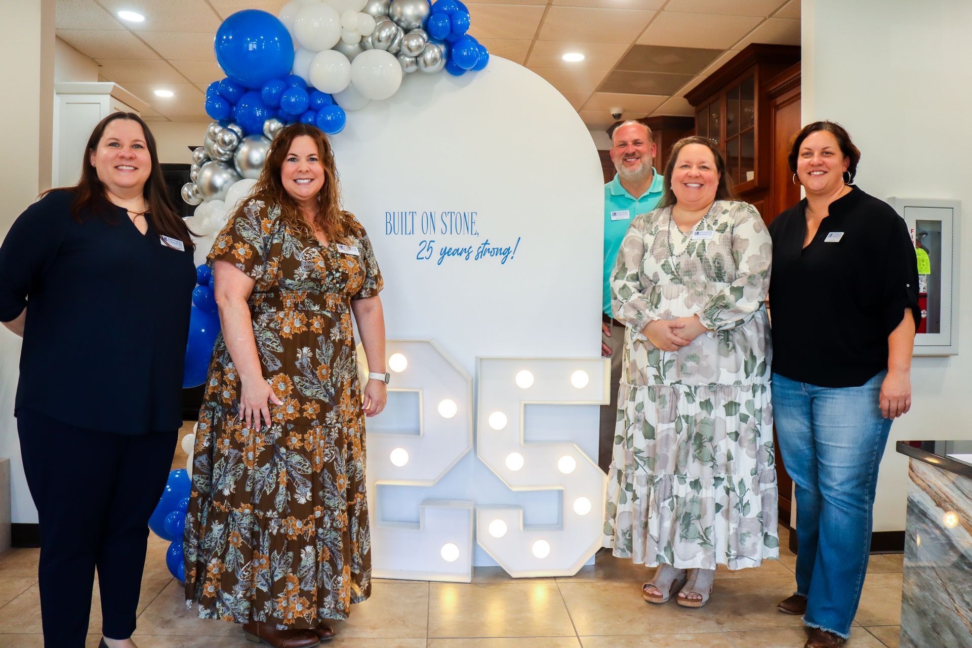 The Johnson family poses indoors beside a blue-and-white balloon display and illuminated “45” anniversary sign.