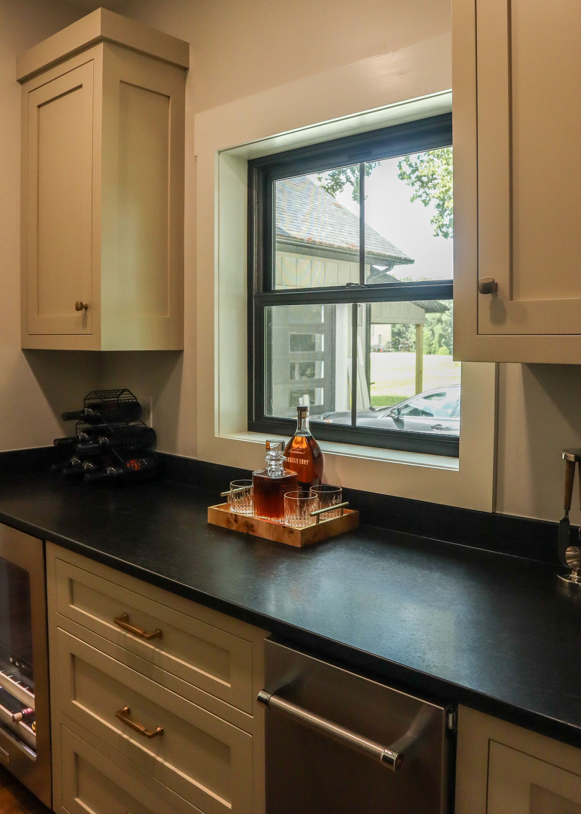 Bright kitchen counter and cabinets beside a window with decorative tray and small items.