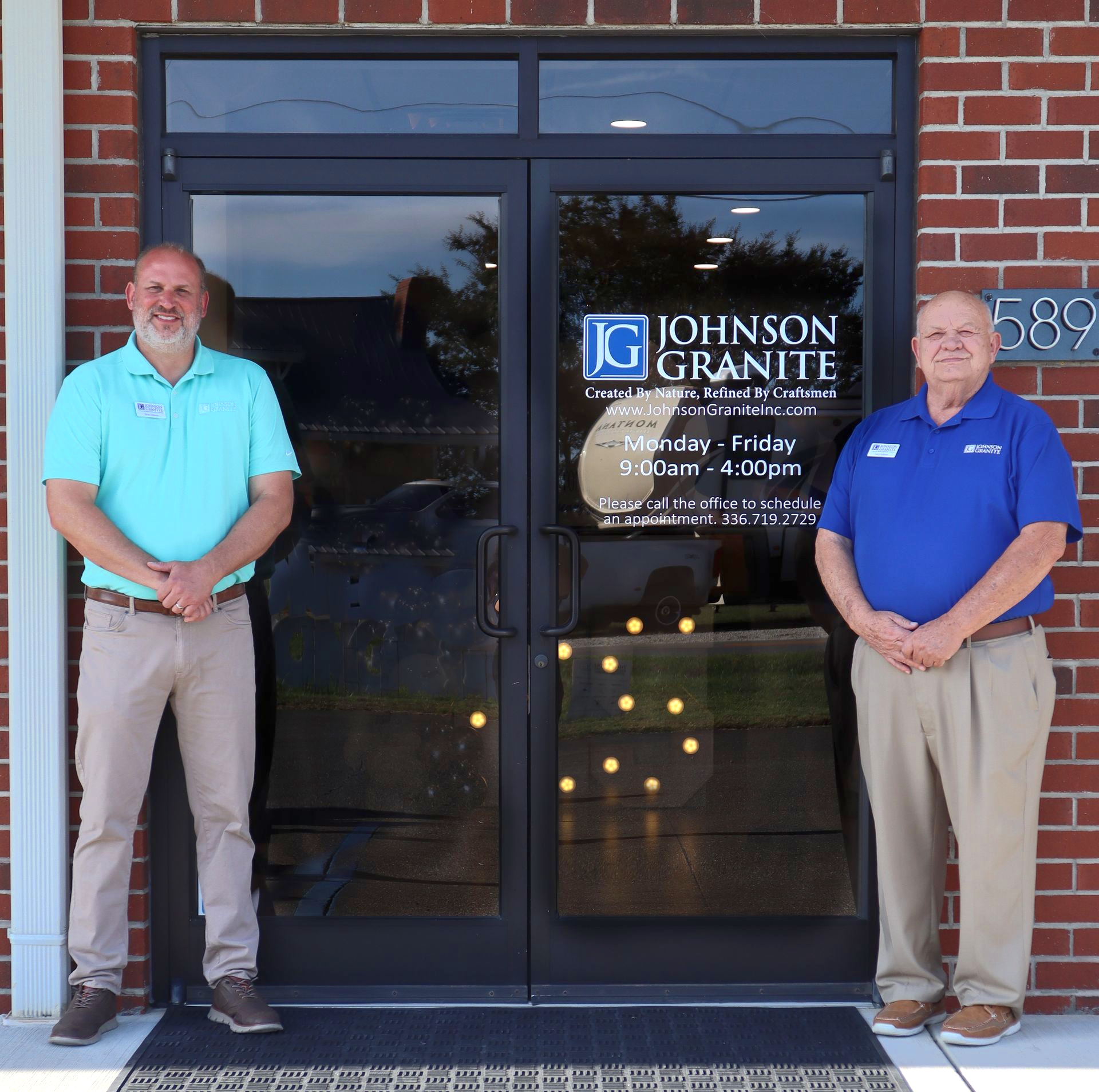 Larry and Briand Johnson standing outside a Johnson Granite storefront with glass doors and a brick facade.
