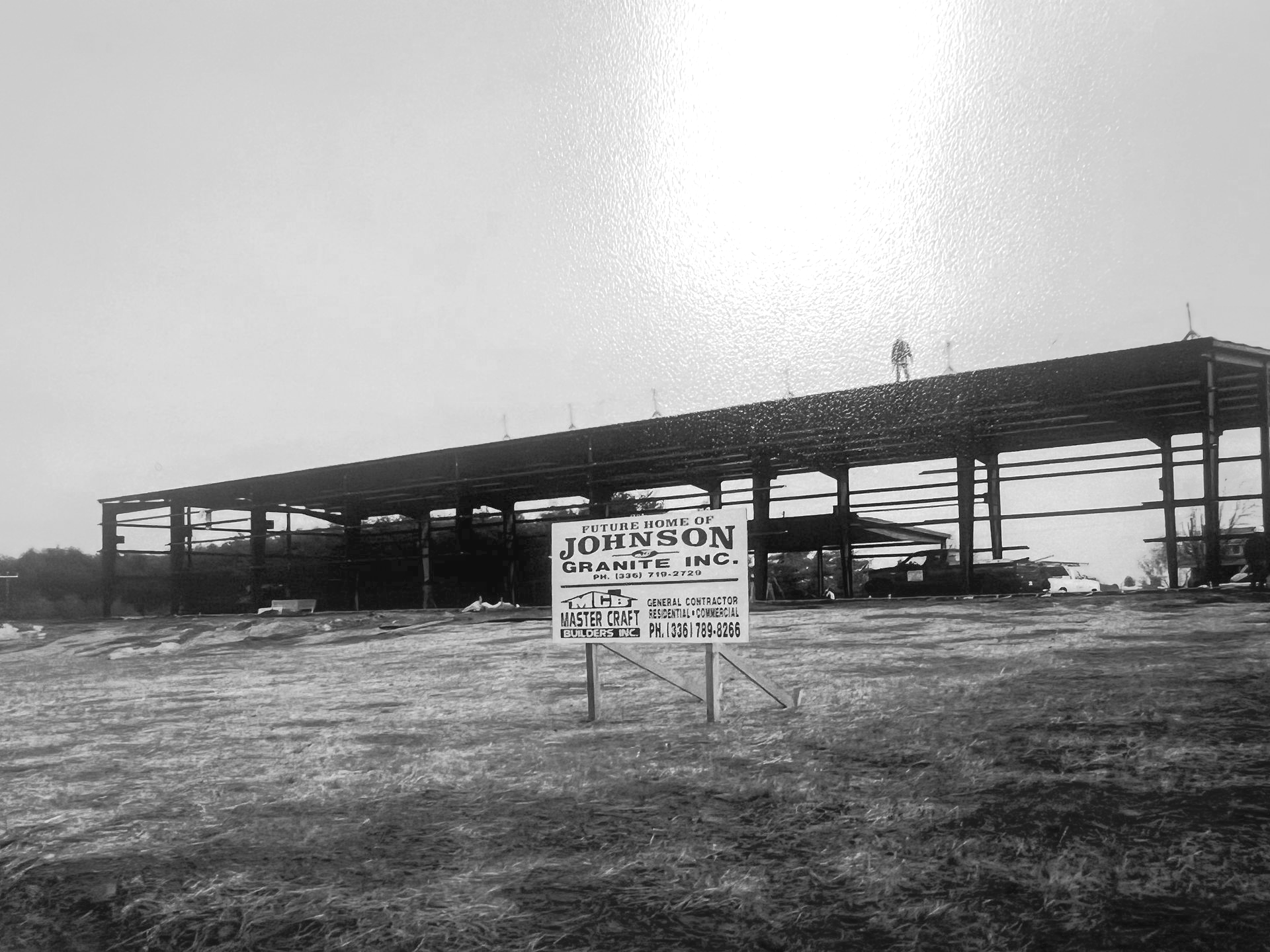 Black-and-white photo of a JGIs expanded building under construction with a sign in front.