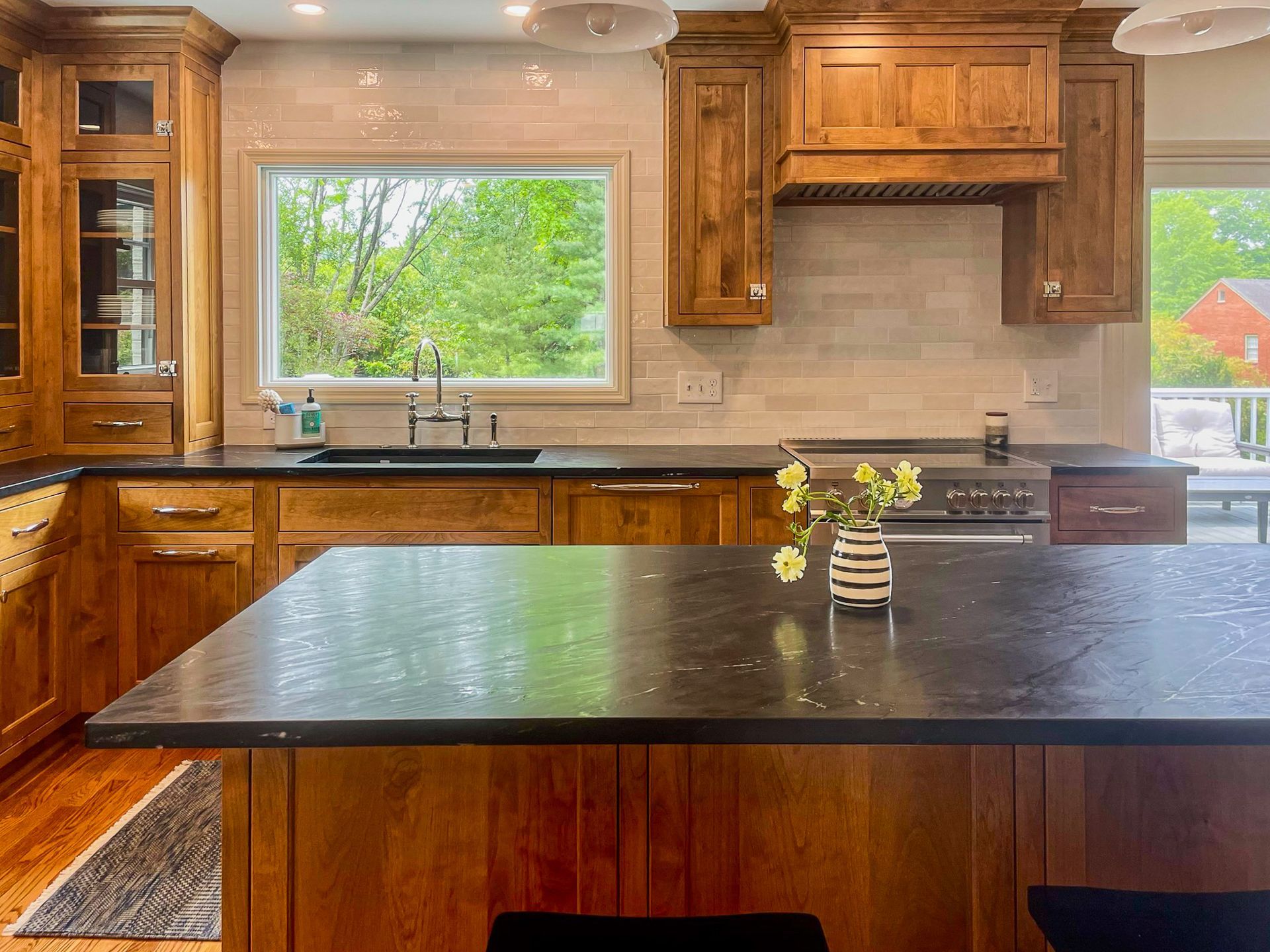 Wooden kitchen with black island countertop, large window, and stainless steel appliances