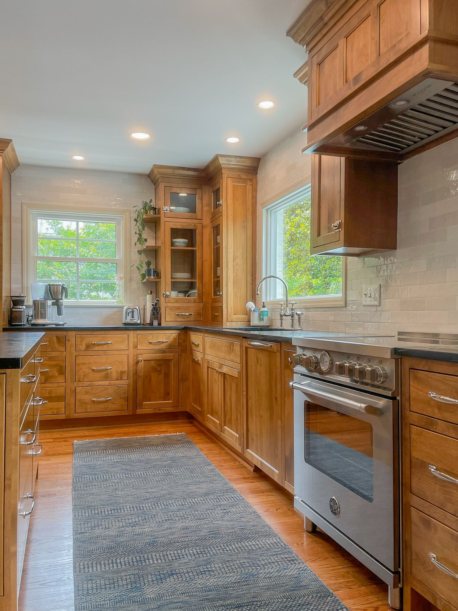 Bright kitchen with wooden cabinets, granite counters, stainless oven, and windows over the sink