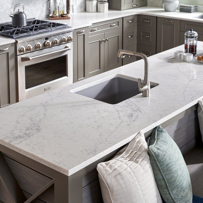 Modern kitchen with stainless steel stove, white marble island, and dark undermount sink