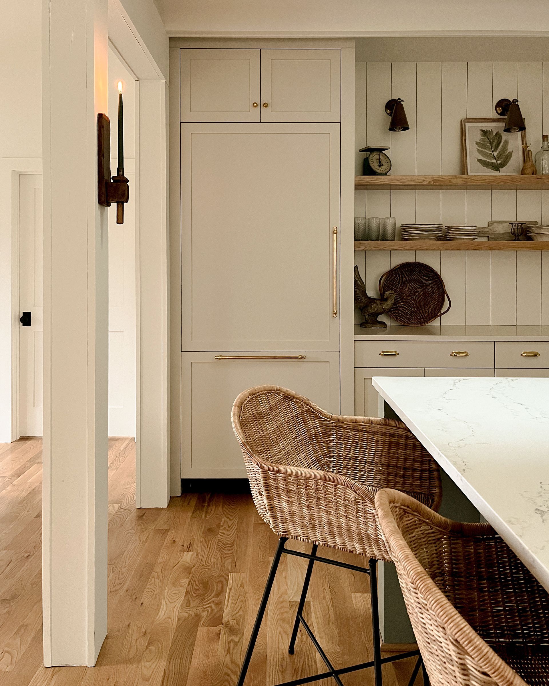 Bright kitchen and dining area with woven chairs, white cabinets, and a table in the foreground