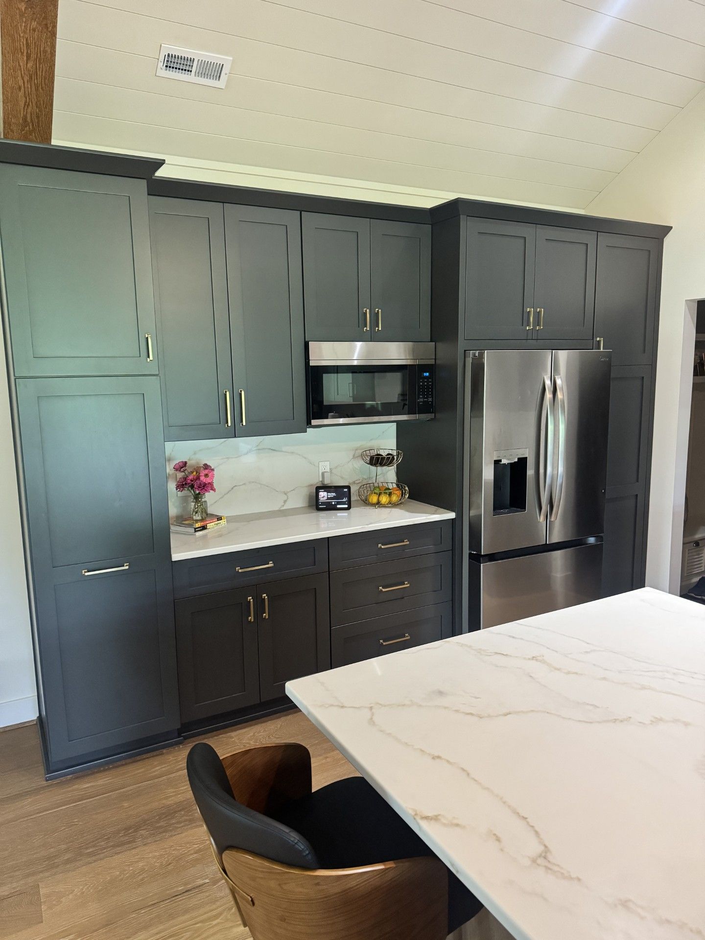Kitchen window over black countertop with pink flowers and wooden cabinets