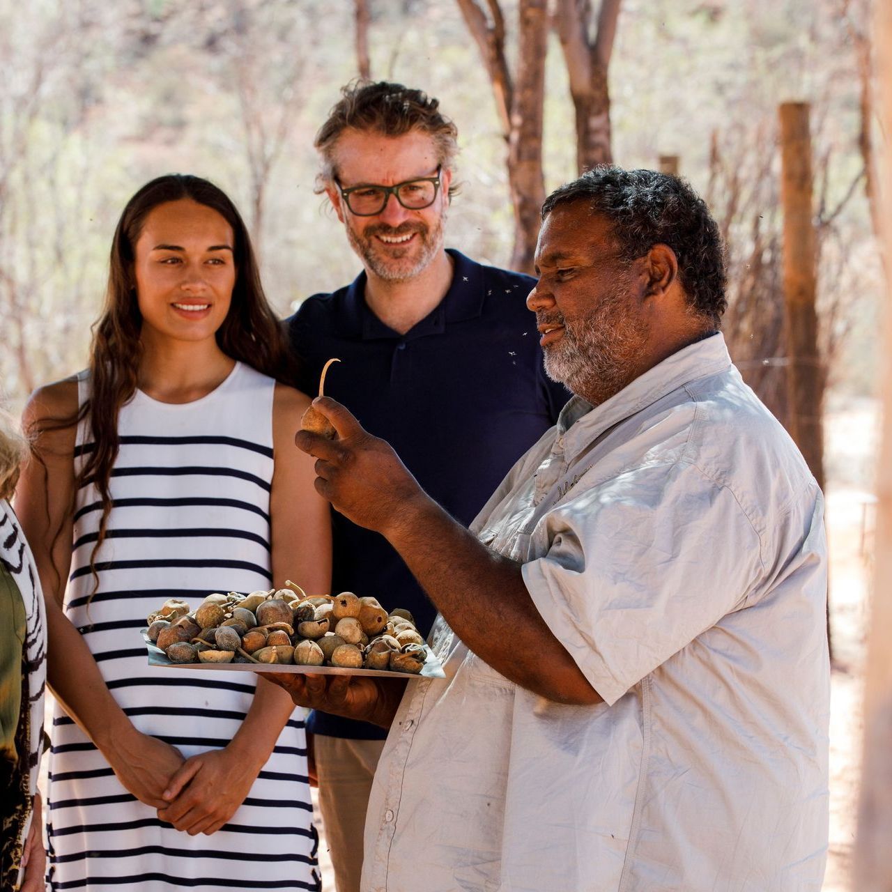 A group of people standing around a man holding a tray of food