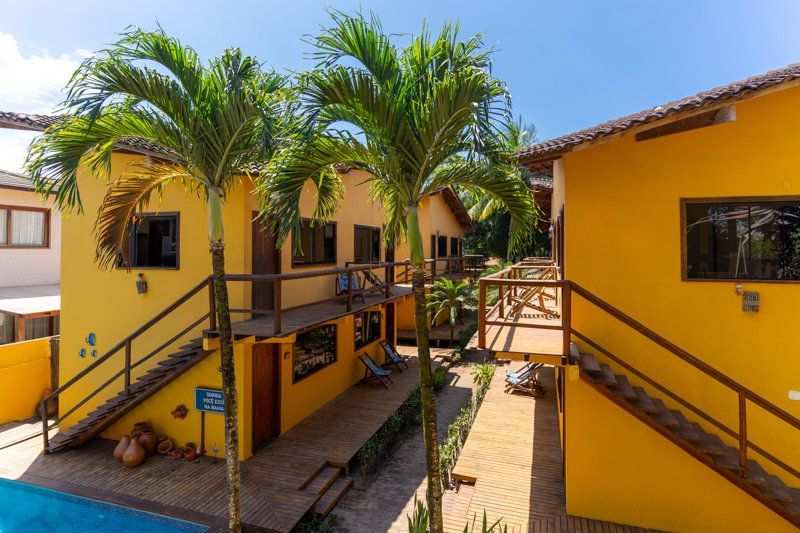 Edifícios amarelos de um resort tropical com palmeiras e passarelas ao redor de um pátio.