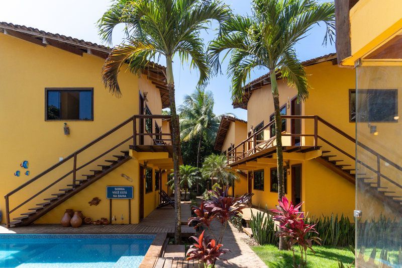 Vilas amarelas de resort com palmeiras, escadas e um pequeno pátio com piscina.