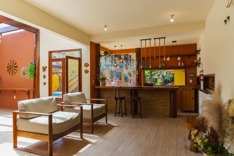 Sala de estar moderna e aconchegante com balcão, banquetas, cadeiras bege e detalhes em madeira em tons quentes.