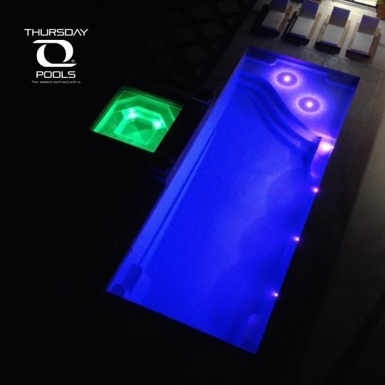 Blue-lit pool table with green-lit side table in a dark room, Thursday Pools logo at top left