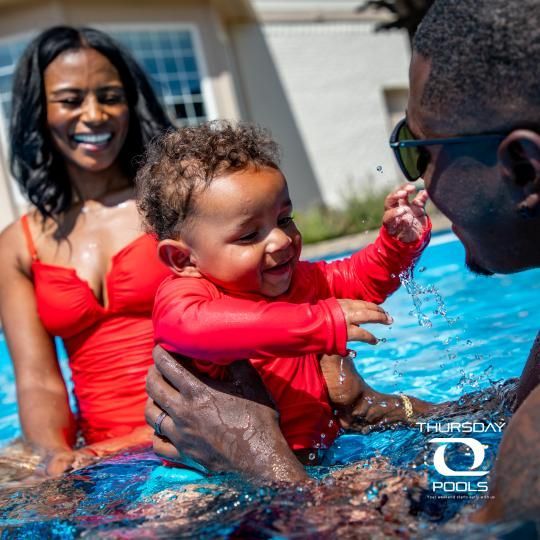 Family laughing together in a swimming pool on a sunny day