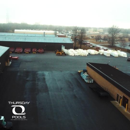 Industrial yard with storage buildings, snow piles, and a cloudy winter skyline.