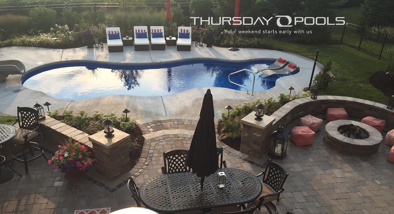 Backyard pool and patio with lounge chairs, fire pit, and hot tub at dusk, labeled Thursday Pools