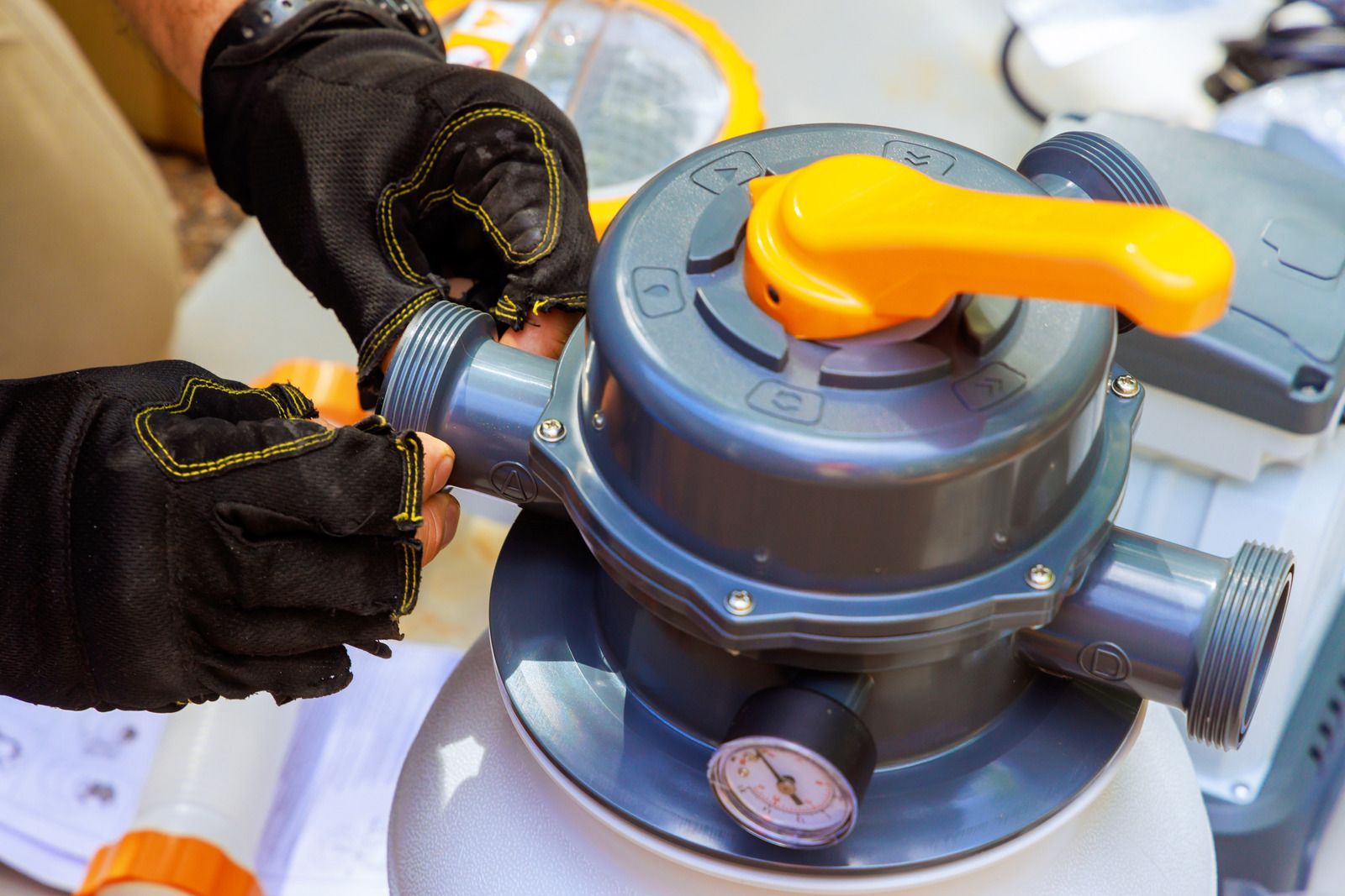Person with black gloves connecting pool filter parts.