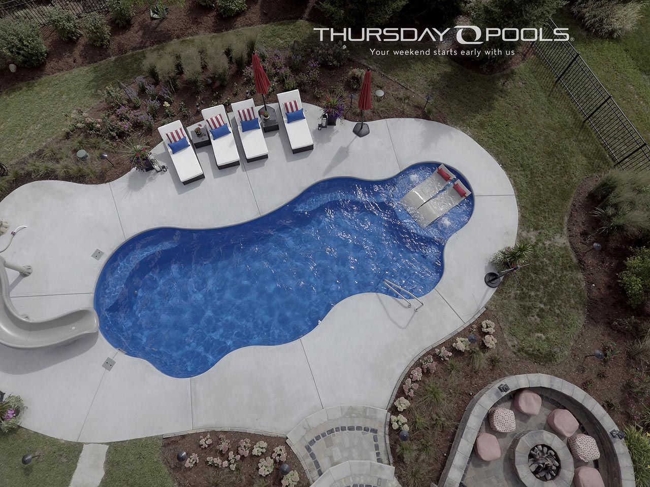 Overhead view of a backyard pool with blue water, white deck chairs, and a hot tub