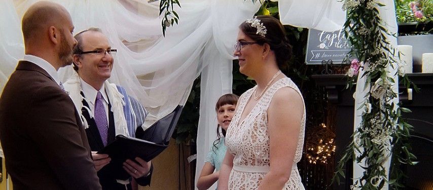 A bride and groom are holding hands during their wedding ceremony.