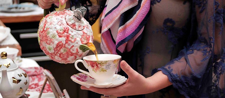 pretty pink hydrangea teapot with butterfly on top pouring tea into a floral tea cup. In bexx secret garden.