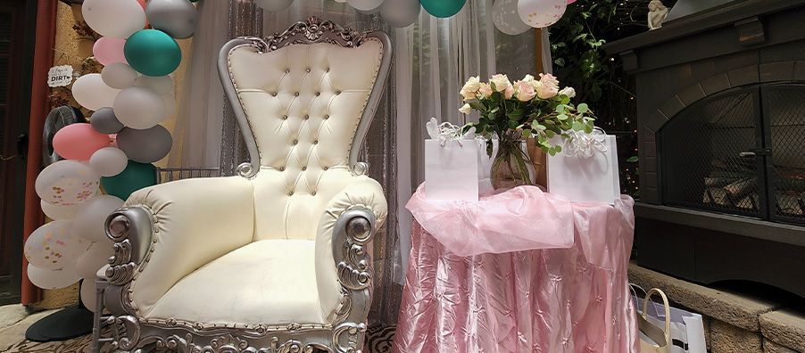 White throne chair with balloon garland roses on pink table with gifts. bexx secret garden 