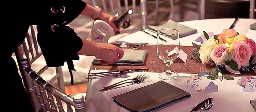 A woman is setting a table for a wedding reception.