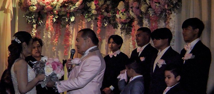 A bride and groom are getting married in front of their wedding party.