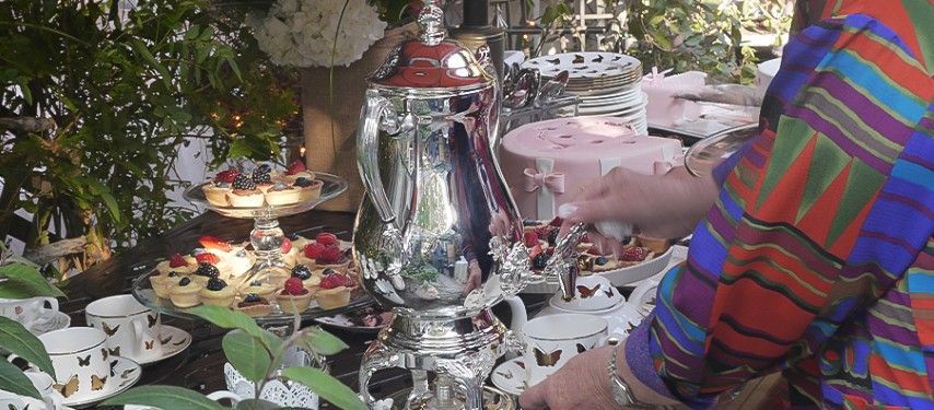 A woman is standing in front of a table filled with plates and cups.