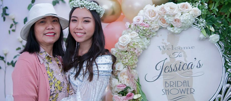 Bride to be with mother in front of custom flower welcome sign. at bexx secret garden.