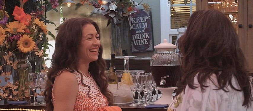 Two women are standing in front of a sign that says keep calm and drink wine
