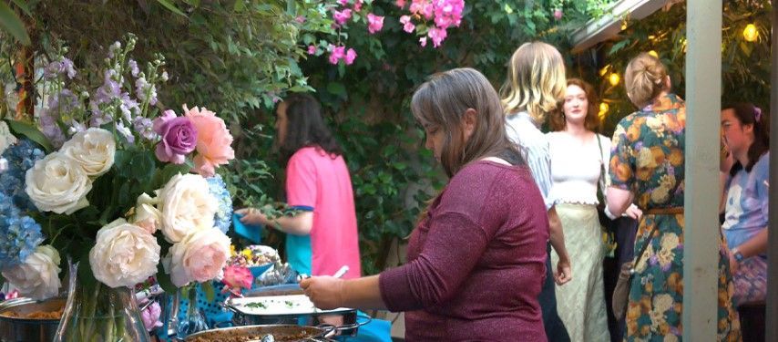 A group of people are standing around a table with flowers.