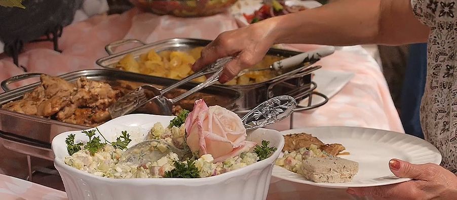 Pink buffet table with tea sandwiches, salads, and roasted chicken  and potatoes 