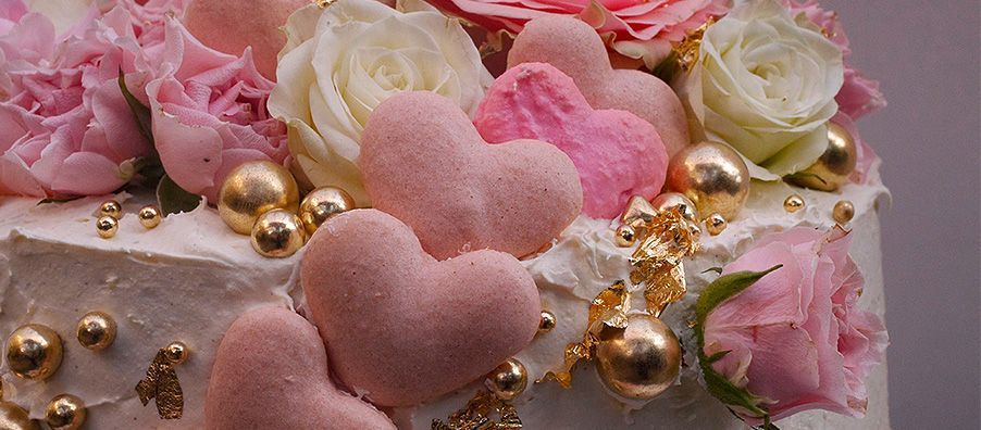 A close up of a cake with hearts and flowers on it.