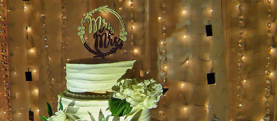 A wedding cake is sitting on a table in front of a wall of lights.