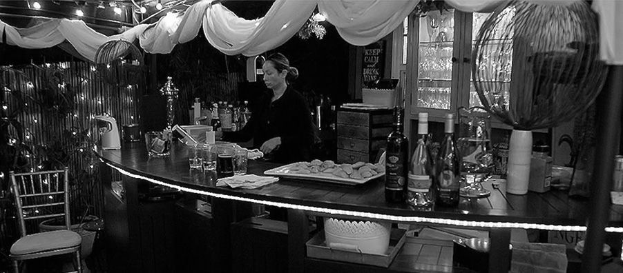A woman is standing behind a bar in a black and white photo.