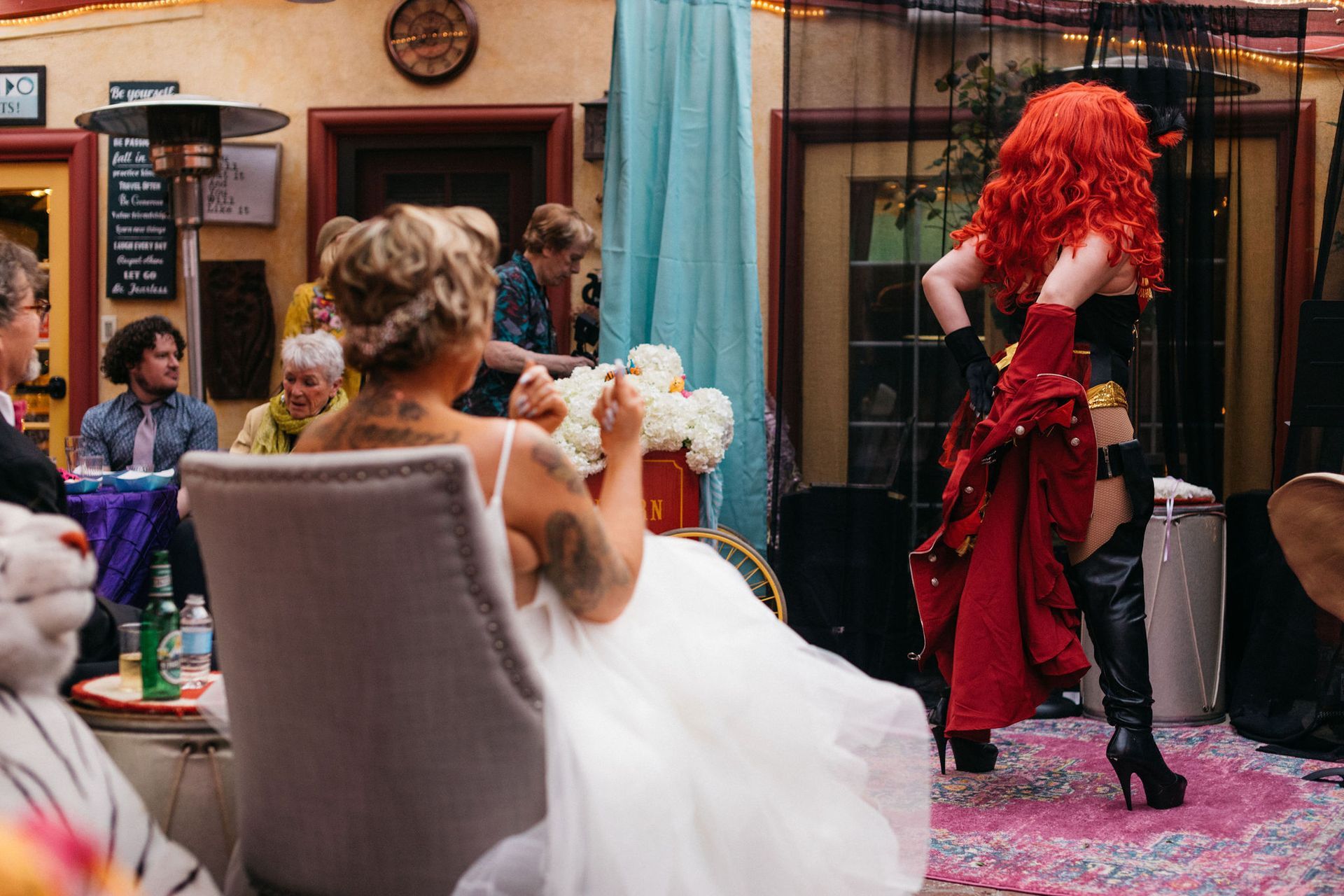 A woman in a red wig is dancing in front of a group of people at a wedding reception.