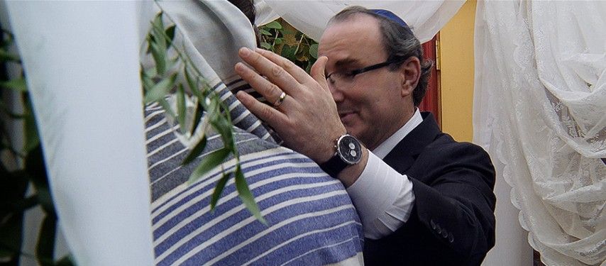 A man in a suit and tie is holding a blue and white striped cloth.
