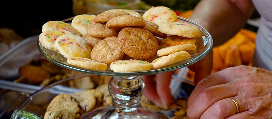 A person is holding a glass plate of cookies.