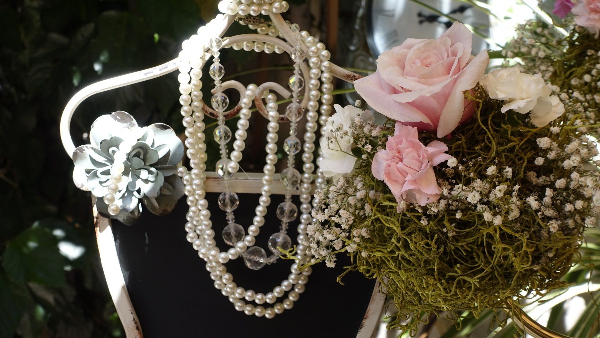 Feminine chalkboard sign with a pearl necklace and flowers on it