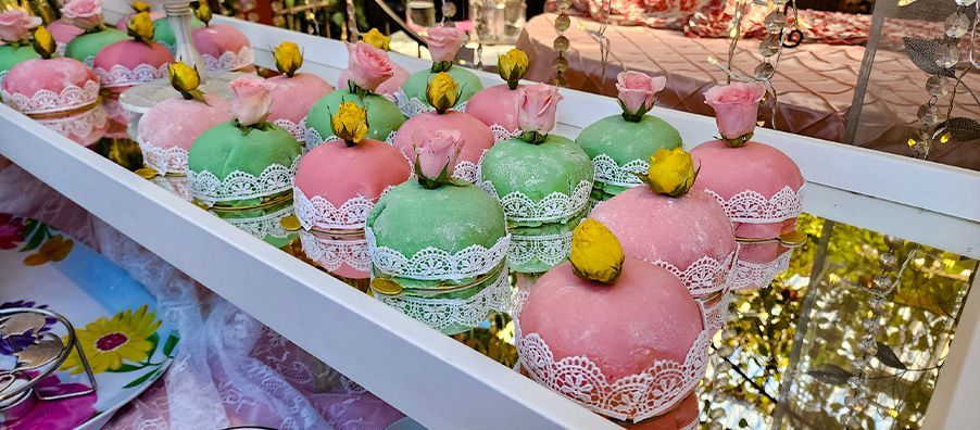 A box of pink and green cupcakes with flowers on top.
